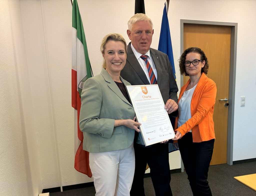 Sandra Postel, Karl-Josef Laumann und Anja Wiedermann präsentieren eine Urkunde