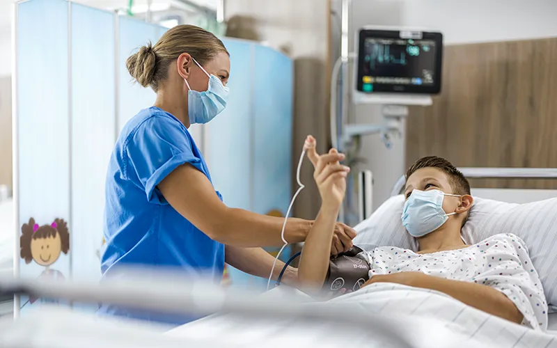Ein Patient in einem Bett liegend wird von einem Fachpersonal betreut