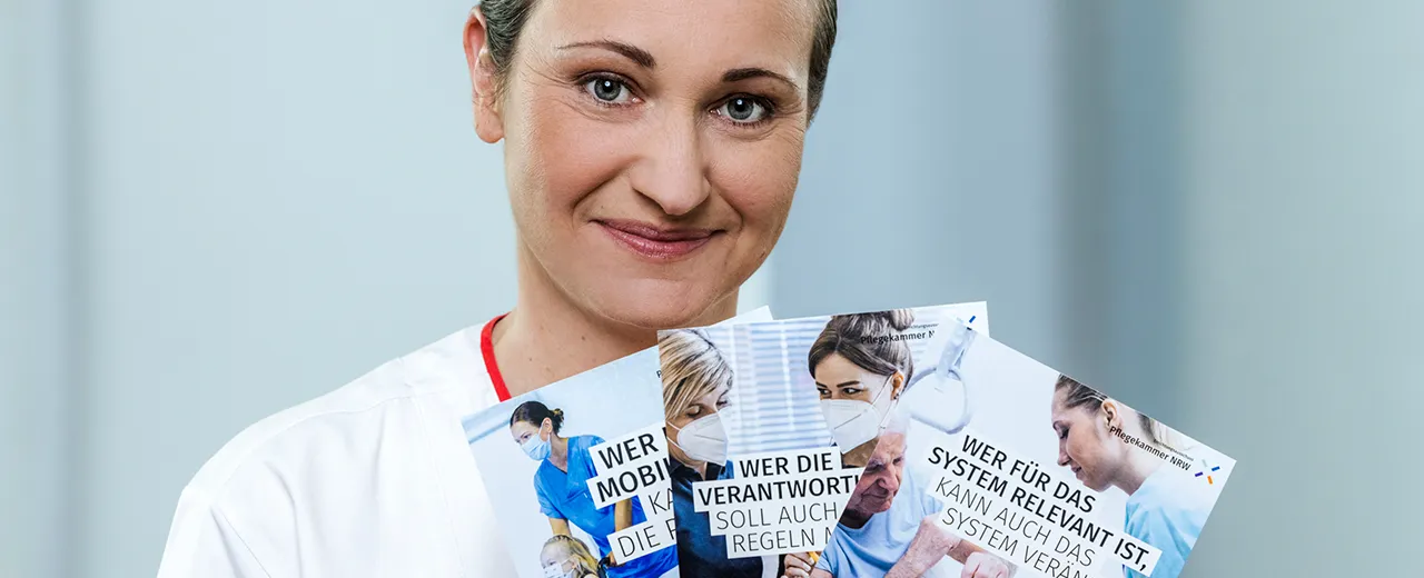 Eine weibliche Person hält Infomaterial der Pflegekammer NRW in der Hand